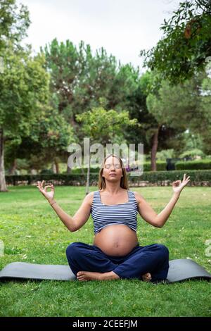 Gravidanza attraente Donna meditare sul tappeto nel parco Foto Stock