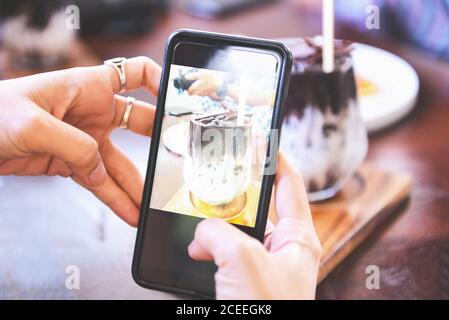 Fotografia alimentare mani donna fare foto cacao bere e torta con smartphone / scattare foto per posta e condivisione sui social network con fotocamera sma Foto Stock