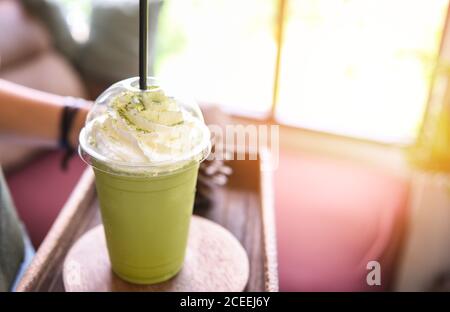 Frullato di tè verde / tè verde Matcha con latte sopra vetro di plastica servito in un caffè Foto Stock