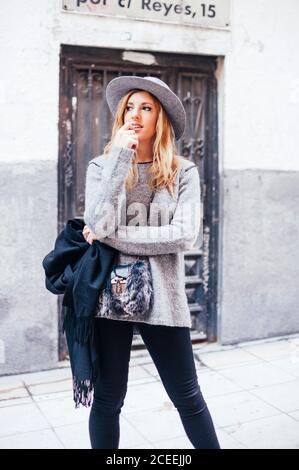 Ritratto di giovane donna bionda che indossa cappello e sciarpa nelle strade di madrid Foto Stock