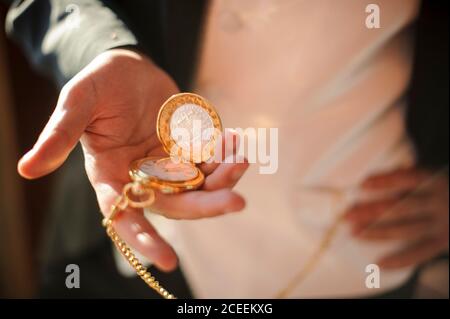 Ritagliare un uomo irriconoscibile in tuta in piedi e guardare il tempo su orologio tascabile. Foto Stock