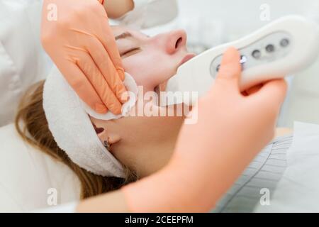 Un estetista professionista esegue una procedura meccanica di pulizia del viso presso la spa. Bella donna caucasica su una procedura cosmetica. Salute Cente Foto Stock