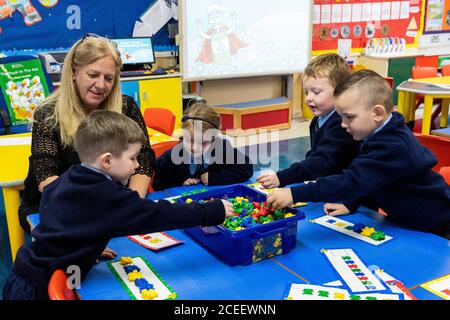 L'insegnante Joanne Conlon con alcuni dei suoi allievi di classe il primo giorno in P1 alla St John the Baptist Primary School a Belfast ovest, poiché quasi tutte le scuole si sono riaperte e oltre 300,000 studenti sono tornati a scuola in Irlanda del Nord per la prima volta da metà marzo. Foto Stock