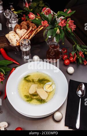 Una ciotola bianca piena di deliziosa zuppa di noodle di pollo Foto Stock