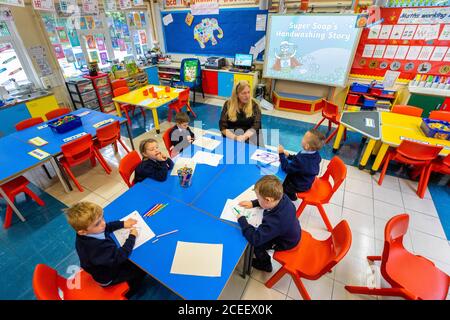 L'insegnante Joanne Conlon con alcuni dei suoi allievi di classe il primo giorno di P1 alla St John the Baptist Primary School a Belfast ovest, poiché quasi tutte le scuole si sono riaperte e oltre 300,000 studenti sono tornati a scuola in Irlanda del Nord per la prima volta da metà marzo. Foto Stock