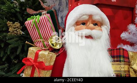 Ritratto fotografico di una bambola giocattolo felice Babbo Natale con una borsa di regali simboleggia l'arrivo di Natale e Capodanno. Atmosfera festosa, concetto di vacanza Foto Stock