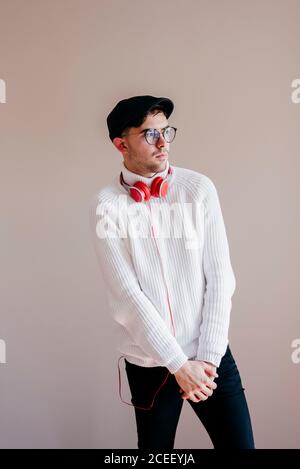 Giovane uomo casual in occhiali con cuffie che guardano lontano. Foto Stock