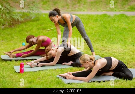 Gruppo di ragazze sportive millenarie che praticano yoga con istruttore a. parcheggio Foto Stock