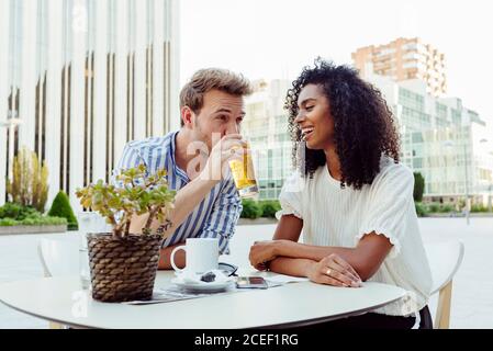 Bella afro-americana donna e bel caucasico uomo sorridendo e guardando l'un l'altro mentre si passa il tempo in caffè all'aperto insieme Foto Stock