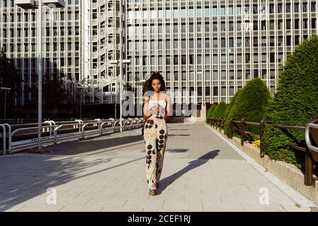 Donna nera usando il telefono sulla strada della città Foto Stock