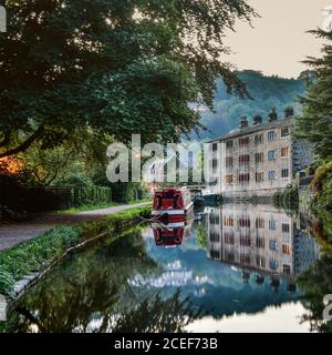 Narrowboat e tessitori cottage riflessi nel canale Rochdale, Hebden Bridge, Pennines, Yorkshire Foto Stock