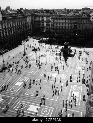 Foto aerea in bianco e nero di vecchia piazza ornata con monumento in il centro e le persone che camminano intorno circondato da un vecchio e bellissimo multipiano edifici in giornata di sole Foto Stock