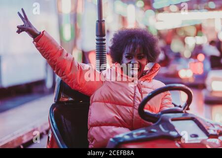 Excited Black Woman auto a cavallo nel parco divertimenti Foto Stock
