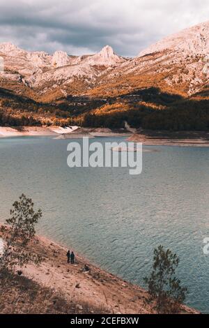 viaggiatori anonimi che si trovano sulla riva di un tranquillo lago di montagna bella giornata nuvolosa Foto Stock