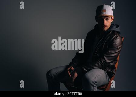 Giovane uomo attraente seduto in uno studio Foto Stock
