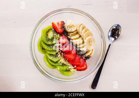 Piatto di ciotola ripiena di kiwi a fette, fragola e banana con semi e noci. Foto Stock