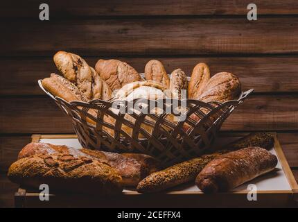 Bella disposizione rustica di cesto con pane e focaccine e baguette su sfondo di legno. Foto Stock