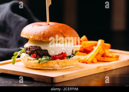 Vista ravvicinata dell'hamburger fresco con polpettine di carne e verdure Posto su tavola di legno con patatine fritte luminose e gustose tavolo di legno scuro Foto Stock