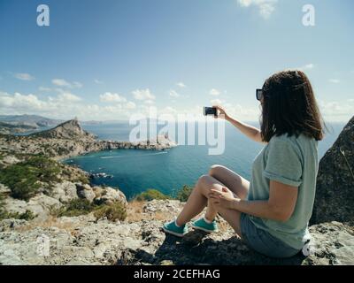 Donna che prende selfie sulla costa Foto Stock