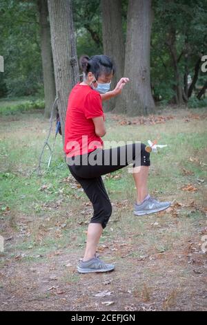 Una donna gioca a Jianzi, uno sport cinese tradizionale in cui i giocatori puntano a mantenere un peso pesante shuttleock in aria utilizzando il loro corpo. Foto Stock