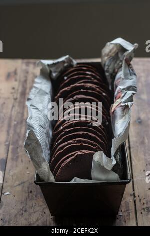 Piccolo rametto di olive asciutte adagiato su un piano di legno vicino al metallo scatola con deliziosi biscotti al cioccolato senza glutine e morbido asciugamano Foto Stock