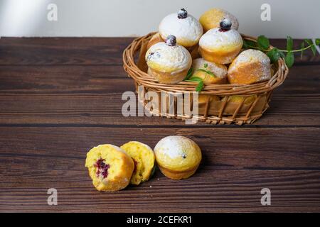 cupcakes con foglie di menta e ribes nero in zucchero in polvere su fondo nero, un cesto di legno con cupcakes e ribes nero . primo piano Foto Stock