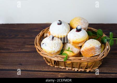 cupcakes con foglie di menta e ribes nero in zucchero in polvere su fondo nero, un cesto di legno con cupcakes e ribes nero . primo piano Foto Stock