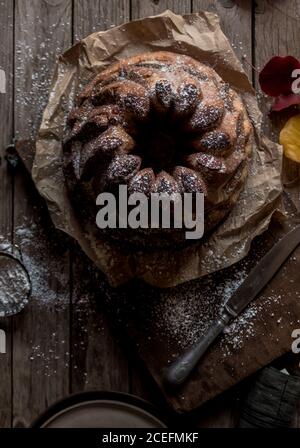 Fresco gustoso Kugelhopf in piedi su carta pergamena su legname stagionato piano portapaziente in prossimità di foglie autunnali asciutte Foto Stock
