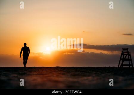 Silhouette di uomo che cammina sulla spiaggia. Foto Stock