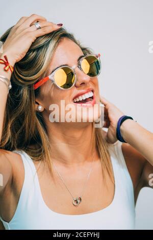 Giovane donna che tocca i capelli e ride Foto Stock