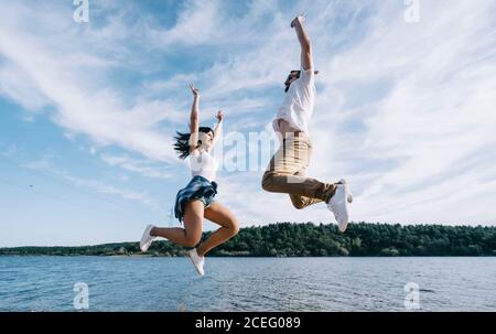 Donna e uomo in abiti casual divertendosi sul lago e ridendo con il cielo blu e la foresta sullo sfondo Foto Stock