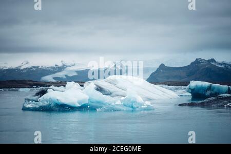 Paesaggio di acqua di mare fredda con iceberg bianco contro cielo nuvoloso, Islanda Foto Stock