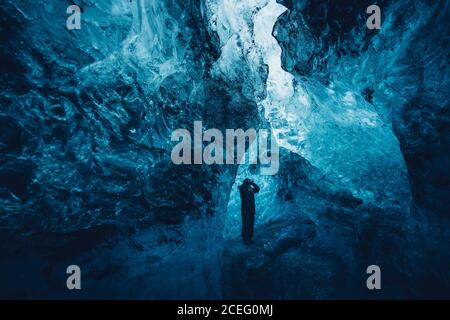uomo in una bella grotta di ghiaccio blu Foto Stock