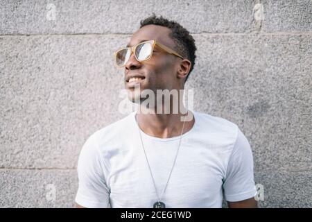 Uomo africano che indossa una camicia bianca e occhiali da sole in posa. Foto Stock