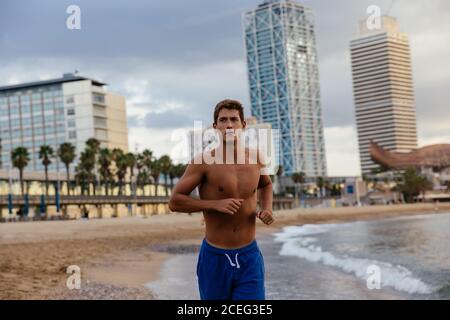 Giovane uomo che corre sulla riva. Foto Stock