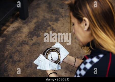 Donna che pulisce un pezzo in un'officina meccanica Foto Stock