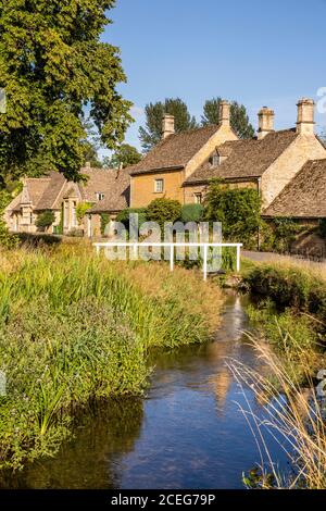 Luce serale su cottage in pietra accanto al River Eye nel villaggio di Cotswold di Lower Slaughter, Gloucestershire UK Foto Stock