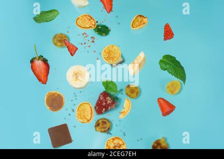 minitola per cereali con fragole fresche, banana, cioccolato, menta di cocco. tendenza all'autoisolamento. levitazione di minuscoli pancake Foto Stock