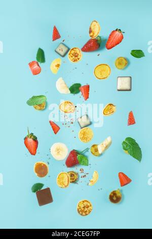 minitola per cereali con fragole fresche, banana, cioccolato, menta di cocco. tendenza all'autoisolamento. levitazione di minuscoli pancake Foto Stock