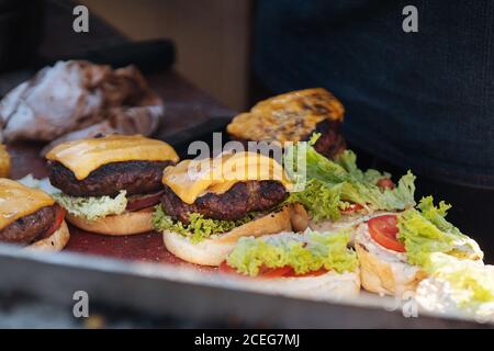 colpo di cuoco senza volto in guanti arrangiando i panini con fresco polpettine di verdure e carne con hamburger di formaggio Foto Stock