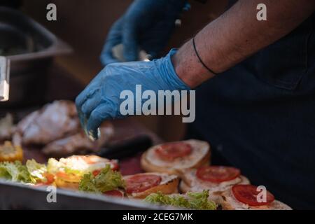 colpo di cuoco senza volto in guanti arrangiando i panini con fresco polpettine di verdure e carne con hamburger di formaggio Foto Stock