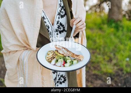 Foto senza volto di Donna con piatto di verdure fresche con filetto di salmone alla griglia e zucchine al pic-nic Foto Stock