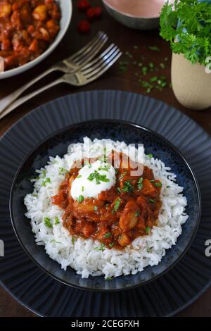 Vista dal piano superiore di un pasto vegetariano verdure e burro chili di fagiolo servito in abbastanza blu ciotola su grande decorativo piastra Foto Stock