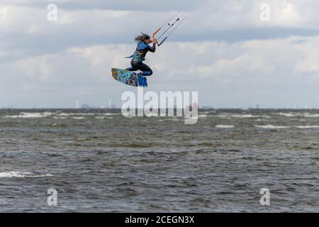 Malmo, Svezia - 23 agosto 2020: Un kitesurfer salta in alto in acqua in una giornata ventosa in cui molte persone cogliano l'opportunità di praticare sport acquatici Foto Stock