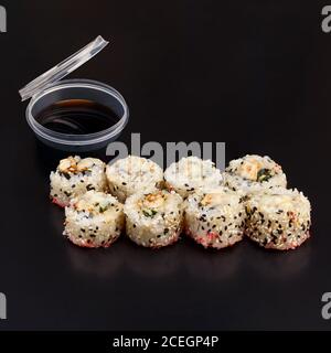 Griglia in chikken al forno a rotoli di yaki su sfondo nero con riflessi. Involtino di sushi con riso, nori, filetto di pollo, salsa di pancetta, cetriolo, parmigiano Foto Stock