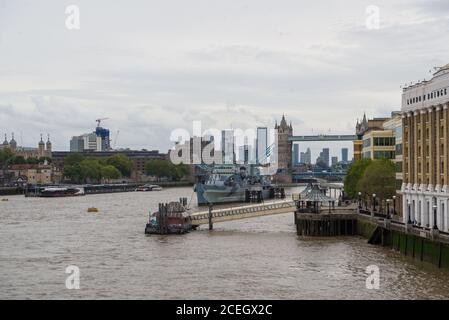 Fiume Tamigi da London Bridge verso Tower Bridge. HMS Belfast e City Pier in primo piano. Torre di Londra e Canary Wharf sullo sfondo. Foto Stock