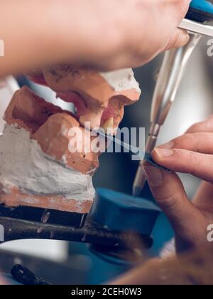 Crop mani di dentista utilizzando la pressa per fare la dentiera gettata in laboratorio. Foto Stock