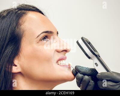 Mano del dentista che sceglie la tintura della dentiera per la donna Foto Stock
