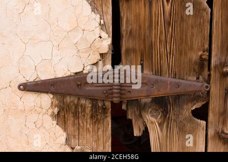 Cerniera arrugginita sulla porta di legno intemperie di un edificio derelitto nella città fantasma virtuale di Thompson Springs, Utah Foto Stock