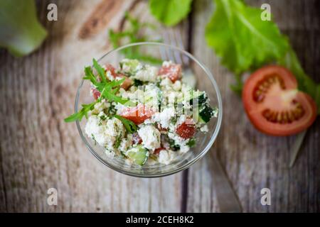 insalata di formaggio fresco caserma con cetrioli e pomodori con erbe in una ciotola Foto Stock